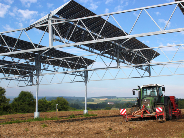 Tracktor unter Agri-PV-Anlage auf bewirtschaftetem Feld Tracktor unter Agri-PV-Anlage auf bewirtschaftetem Feld